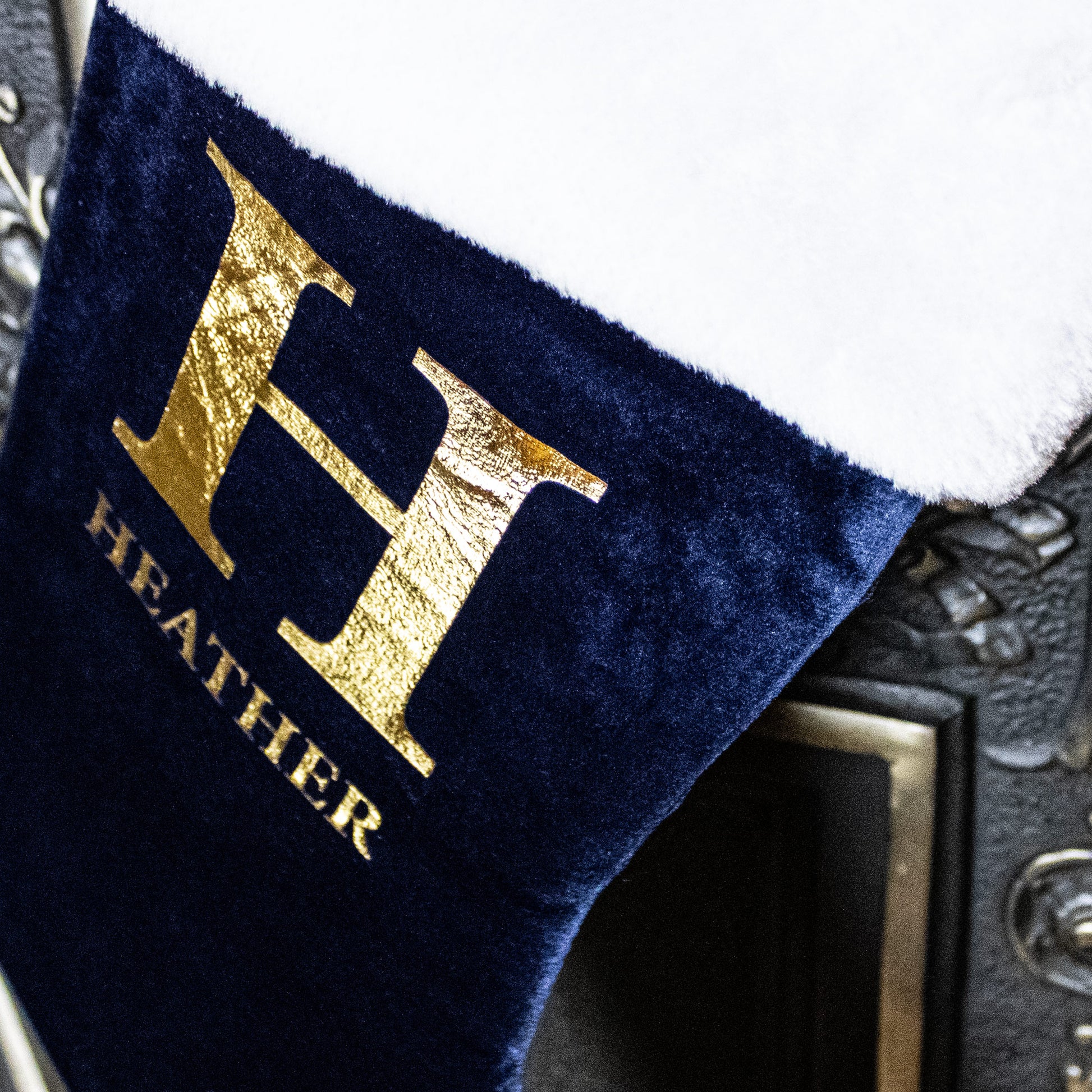 Navy blue towel with gold letter 'H' and text 'HEATHER' on a textured background
