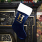 Navy Christmas stocking with gold 'H' and 'HEATHER' text, hanging on a decorative fireplace.