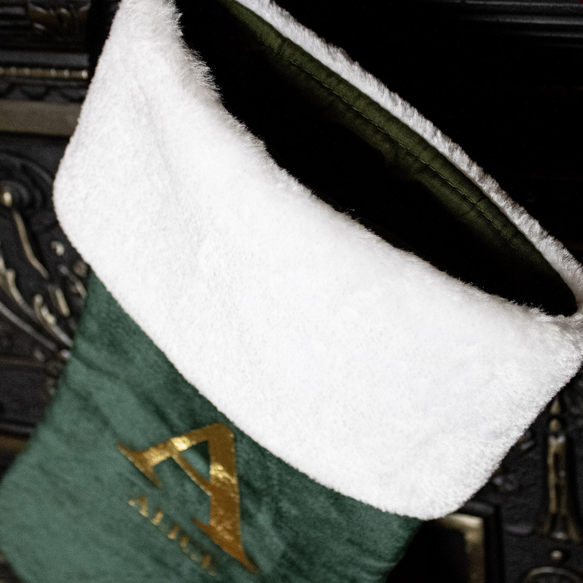 Green stocking with white cuff and gold letter 'A' on a dark background