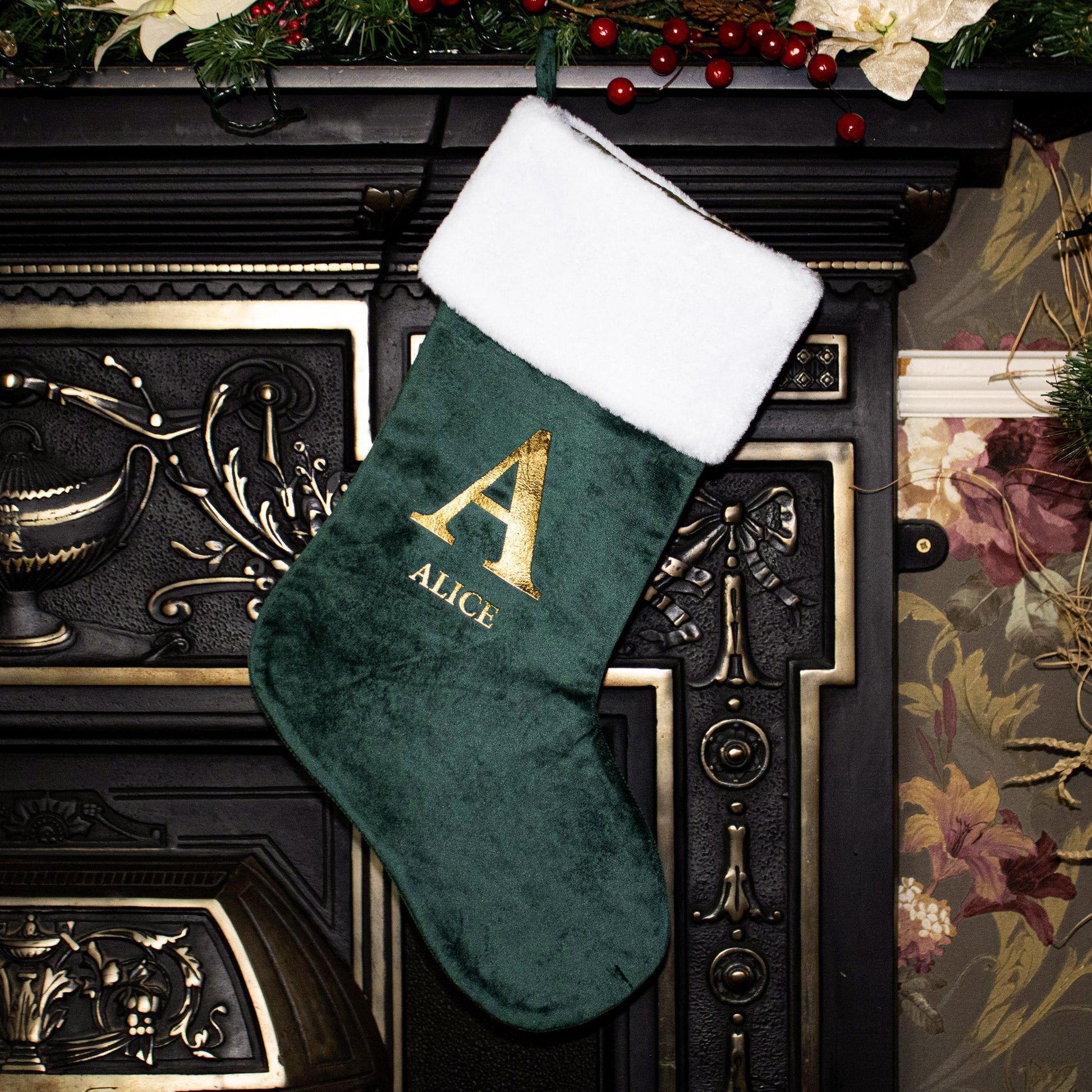 Green Christmas stocking with gold letter 'A' and name 'Alice' on a decorative fireplace.