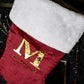 Red Christmas stocking with gold letter 'M' and name 'MATTHEW' on a dark background